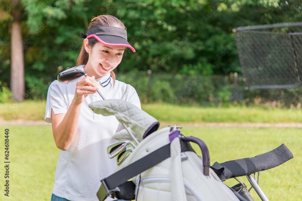 ゴルフ場でゴルフバッグにドライバーを入れる女性ゴルファー
