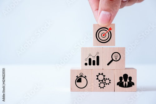 Goal and target, success and business target concept, hand stack woods block step on the table with icon Action plan, project management, company strategy development.