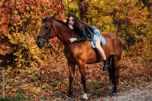 Beautiful young woman posing on a horse in a beautiful autumn forest
