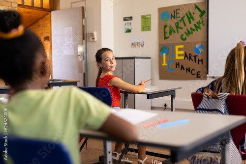 Portrait of happy caucasian schoolgirl in diverse elementary school class