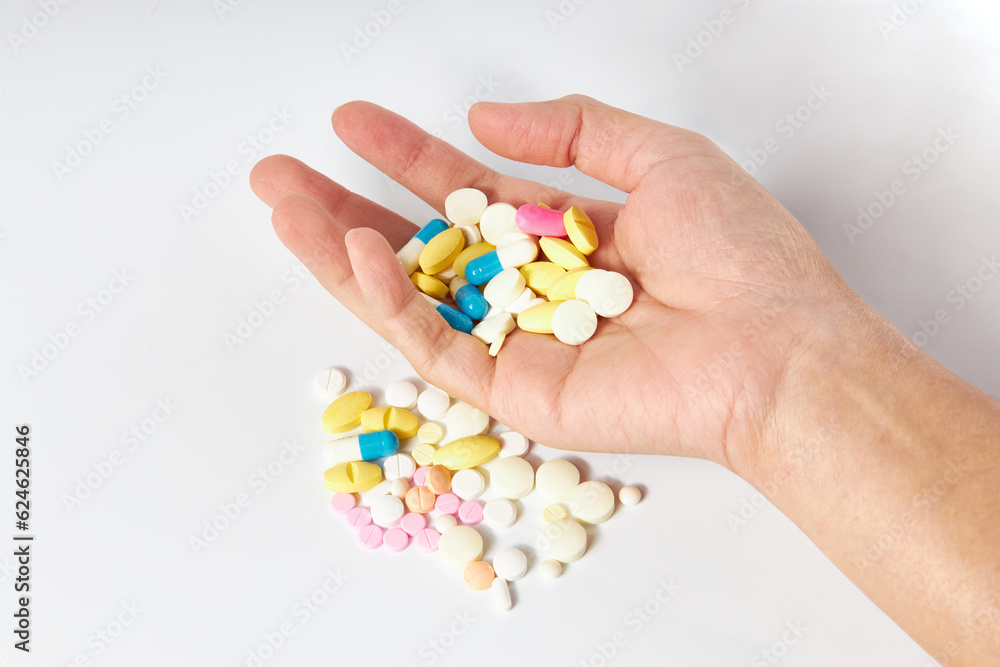 Hand holding A lot of pills different colors (white, pink, orange and blue color) and shapes on a white background. Antipyretics, painkillers and antibiotics. Take medicine overdose. kill oneself. Hand holding A lot of pills different colors (white, pink, orange and blue color) and shapes on a white background. Antipyretics, painkillers and antibiotics. Take medicine overdose. kill oneself.