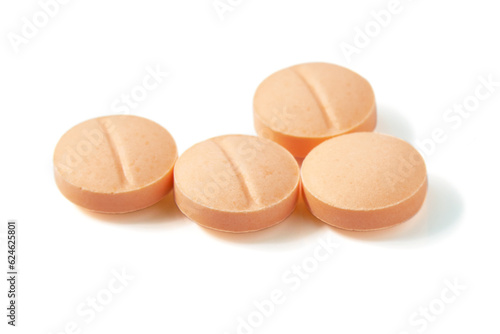 Many Circle-shaped orange pills isolated on a white background.