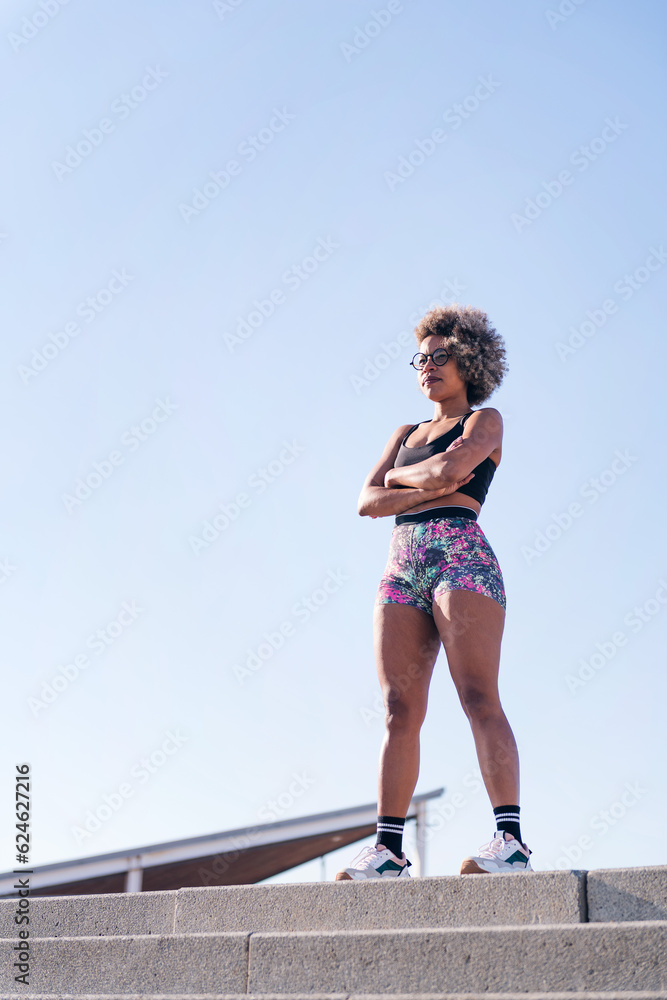 vertical portrait of an african american strong woman with sportswear standing outdoors with arms crossed, concept of sports and active lifestyle, copy space for text vertical portrait of an african american strong woman with sportswear standing outdoors with arms crossed, concept of sports and active lifestyle, copy space for text
