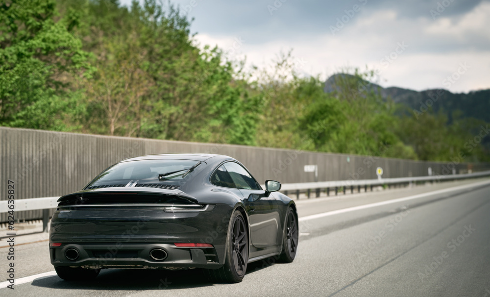 Fototapeta premium Sleek Black German Roadster. Brand New Luxury Carrera Sports Car on the Highway. Aerodynamic beast on the autobahn in Germany.