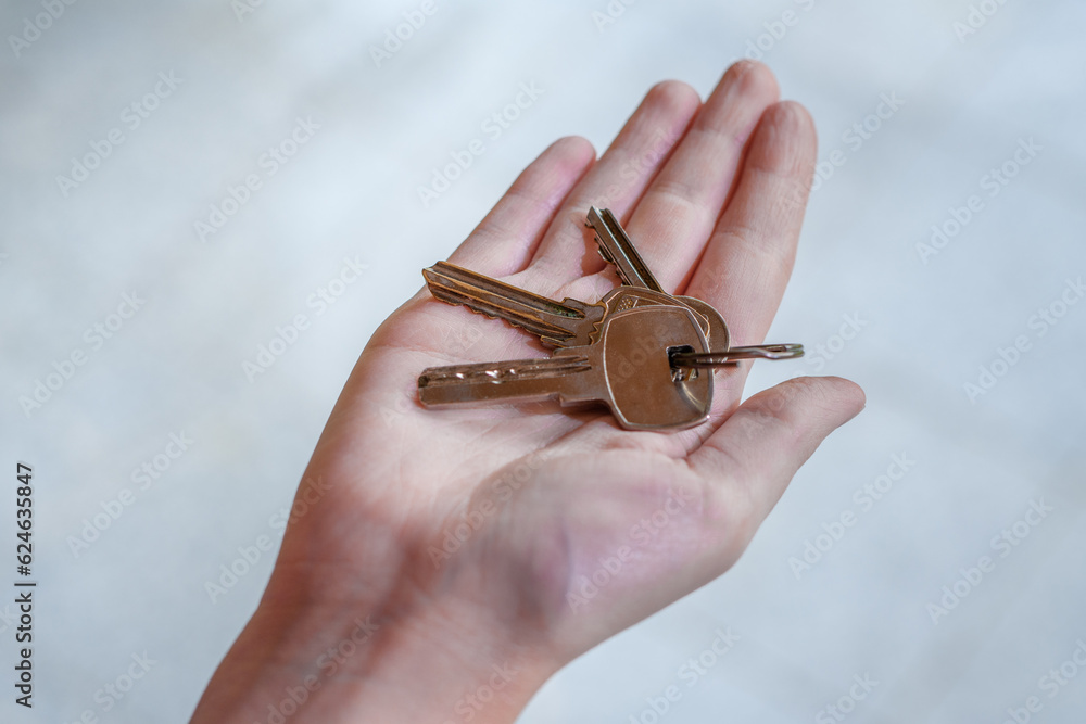 Pęk srebrnych kluczy do nowego mieszkania trzymany w dłoniach 