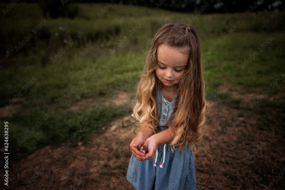 Little girl holding tiny frog and smiling in grassy field Little girl holding tiny frog and smiling in grassy field