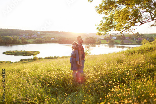 man and woman stand embracing in field of flowers in rays of sun