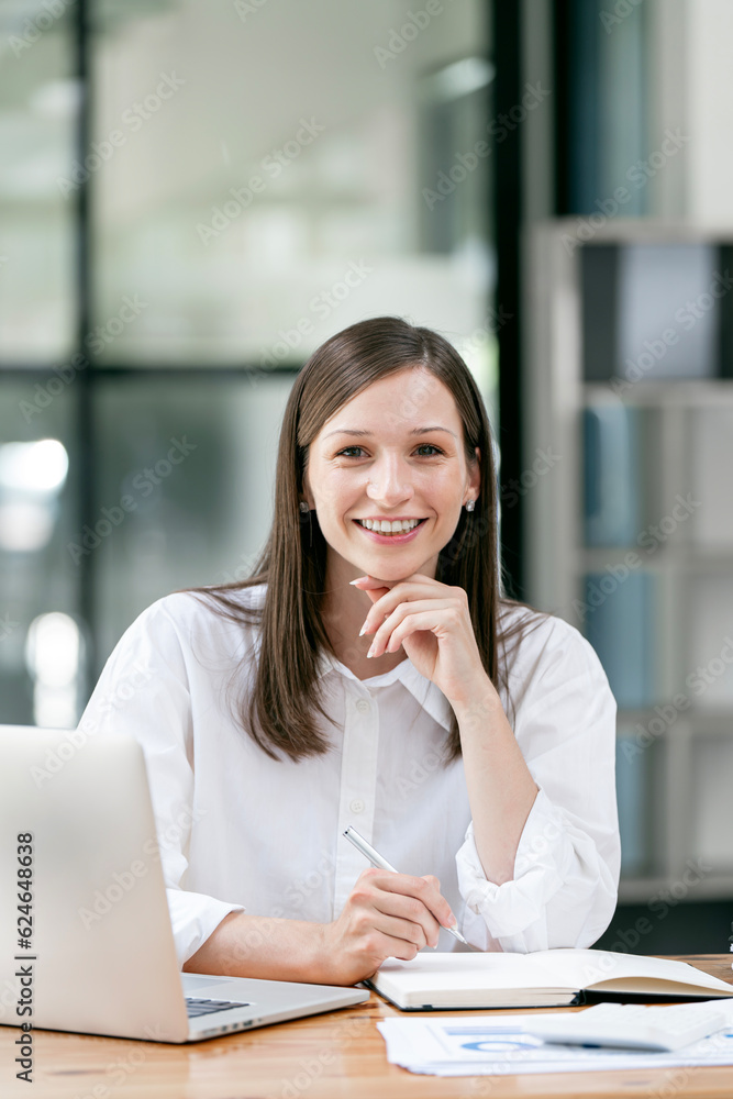 Young female entrepreneur working on a laptop in a modern workspace. Young female entrepreneur working on a laptop in a modern workspace.