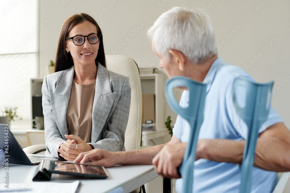 Fototapeta premium Insurance agent discussing conditions with senior man during their meeting in office
