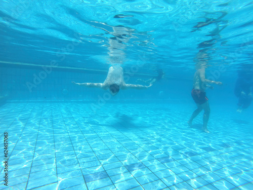 Underwater photo of people diving and swimming in the pool. © Amel