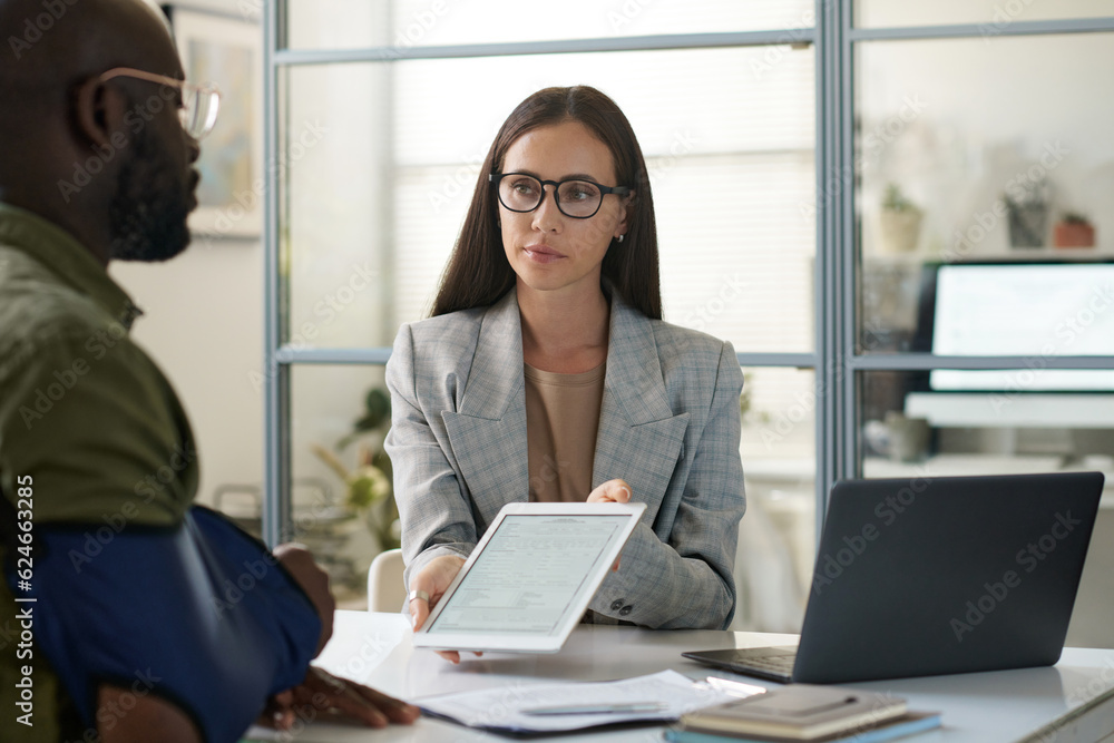 Insurance agent with digital tablet signing contract with client during meeting in office Insurance agent with digital tablet signing contract with client during meeting in office
