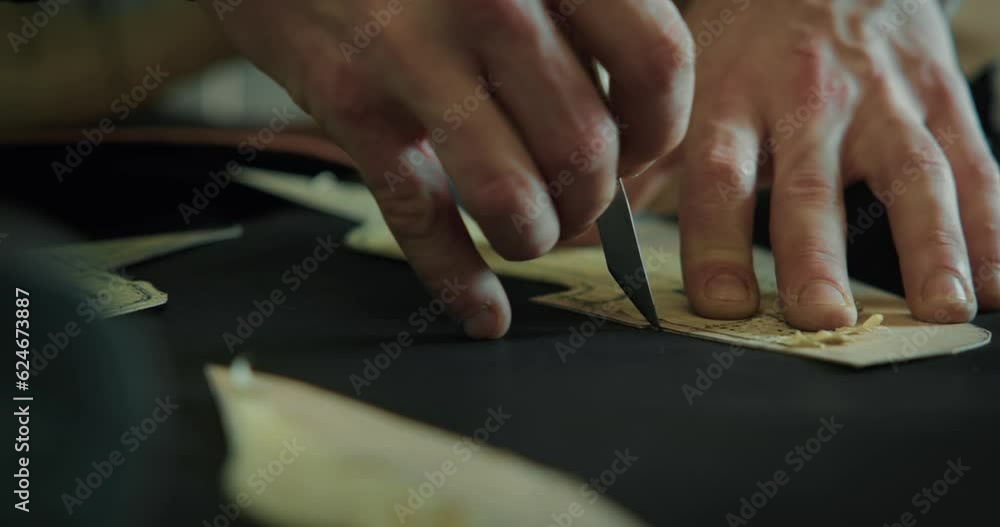 Close-up of a shoemaker cutting out leather pieces on table at the workshop. Close-up of a shoemaker cutting out leather pieces on table at the workshop.