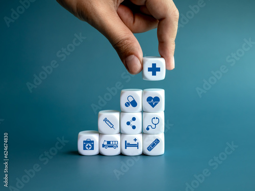 Healthcare medical, wellness plan and insurance concept. Health, care and medical element icon symbols on clean white blocks stacking as a graph arranged by doctor's hand on blue background. photo