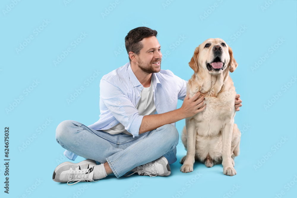Man hugging with adorable Labrador Retriever dog on light blue background. Lovely pet Man hugging with adorable Labrador Retriever dog on light blue background. Lovely pet