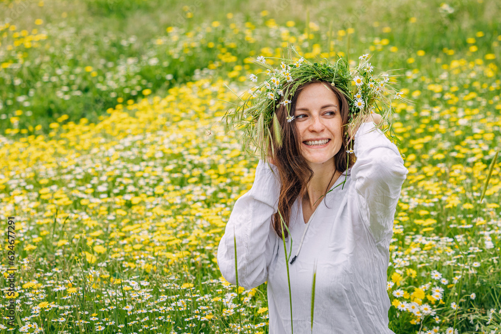 Happy girl in chamomile flower wreath at natural meadow outdoors Happy girl in chamomile flower wreath at natural meadow outdoors
