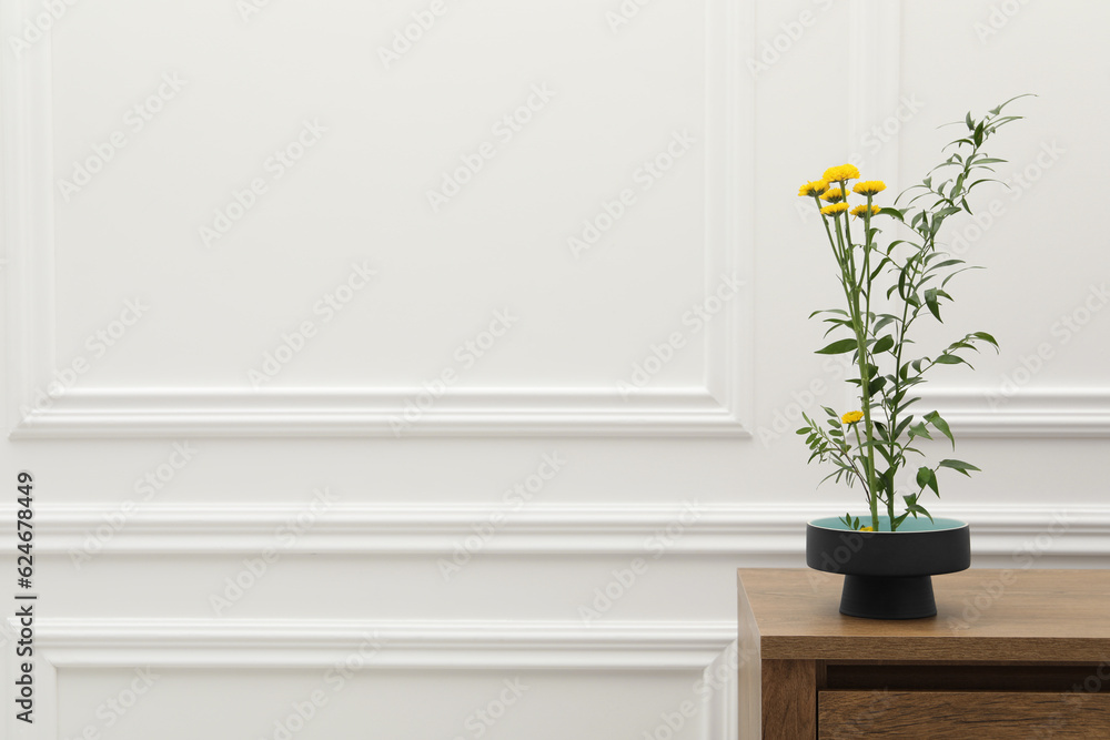Fototapeta premium Ikebana art. Beautiful yellow flowers and green branch carrying cozy atmosphere at home, space for text