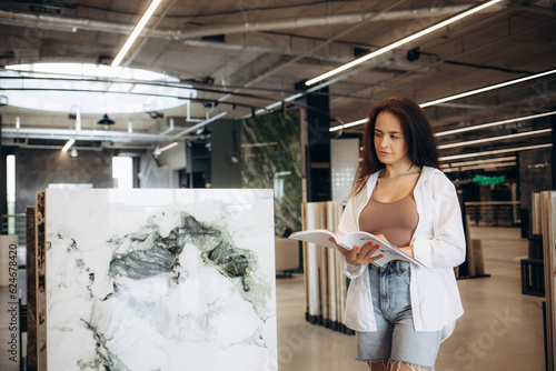 a woman chooses a tile using a tile catalog in a store