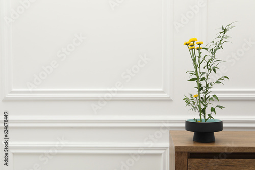 Ikebana art. Beautiful yellow flowers and green branch carrying cozy atmosphere at home, space for text © New Africa