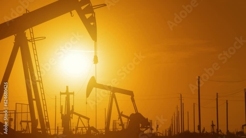The sun rises behind a large oil field in California.