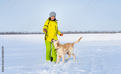 Smiling woman with cute young retriever dog on winter walk