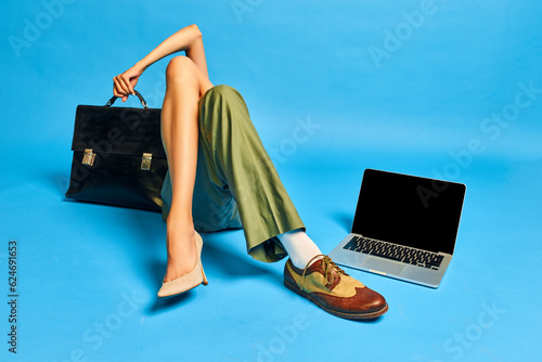 Teamwork. Male and female body parts. Legs in boots and heels with briefcase and laptop against blue studio background. Concept of creativity, business, fashion, surrealism, imagination, ad. Pop art