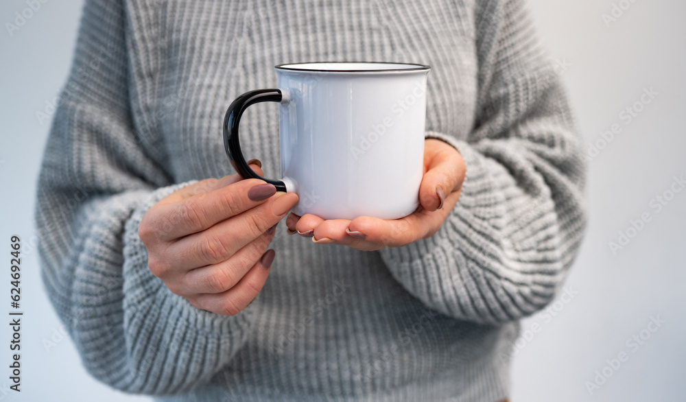 Person holding mug with hot beverage in hands. Girl with rustic cup in winter time Person holding mug with hot beverage in hands. Girl with rustic cup in winter time