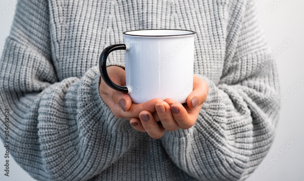Person holding mug with hot beverage in hands. Girl with rustic cup in cold time closeup Person holding mug with hot beverage in hands. Girl with rustic cup in cold time closeup