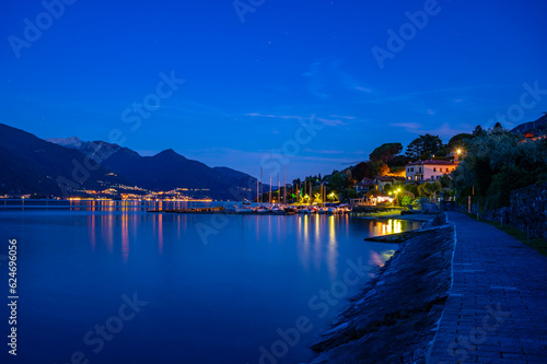 Il paese di Pianello del lario  sul lago di Como  e la passeggiata lungo il lago  all imbrunire. Alpi  montagne e paesi del lago in lontananza.