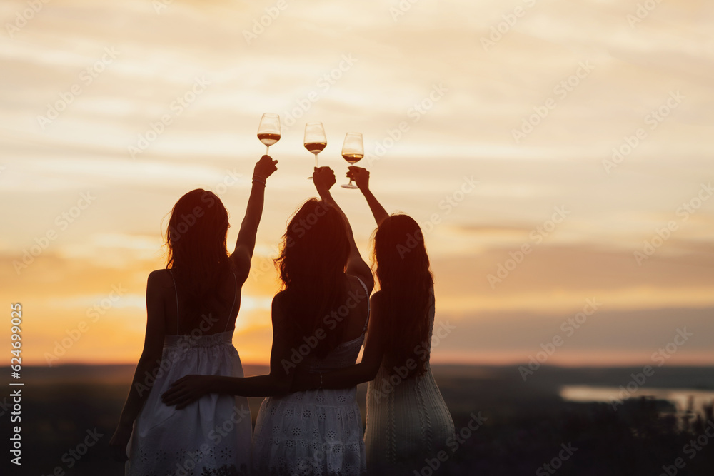 Young girlfriends enjoying their time together on a picnic at amazing sunset.