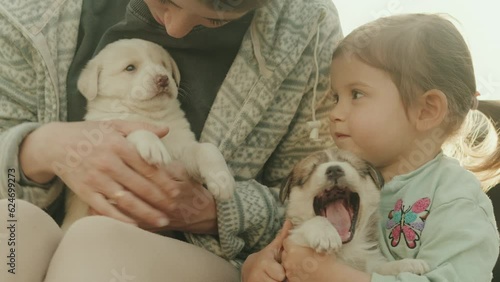 Cutebaby girl with her mother caressing and taking care of a puppy. Mother nature. Funny puppy.