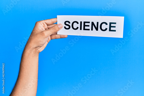 Hand of caucasian man holding paper with science word over isolated blue background