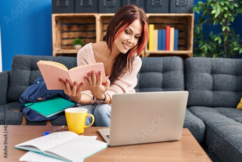 Young caucasian woman student sitting on sofa reading book at home © Krakenimages.com