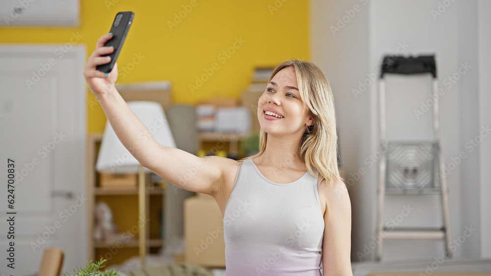 Young blonde woman make selfie by smartphone standing at new home Young blonde woman make selfie by smartphone standing at new home