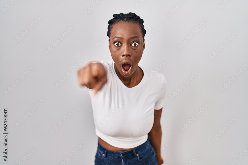 Beautiful black woman standing over isolated background pointing with finger surprised ahead, open mouth amazed expression, something on the front Beautiful black woman standing over isolated background pointing with finger surprised ahead, open mouth amazed expression, something on the front