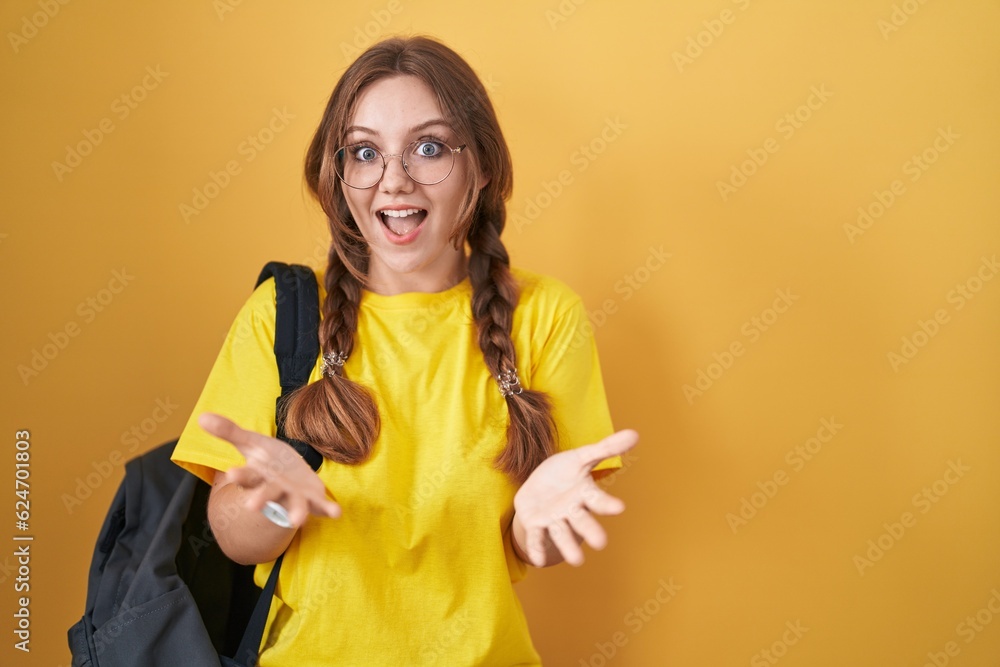 Young caucasian woman wearing student backpack over yellow background smiling cheerful with open arms as friendly welcome, positive and confident greetings Young caucasian woman wearing student backpack over yellow background smiling cheerful with open arms as friendly welcome, positive and confident greetings
