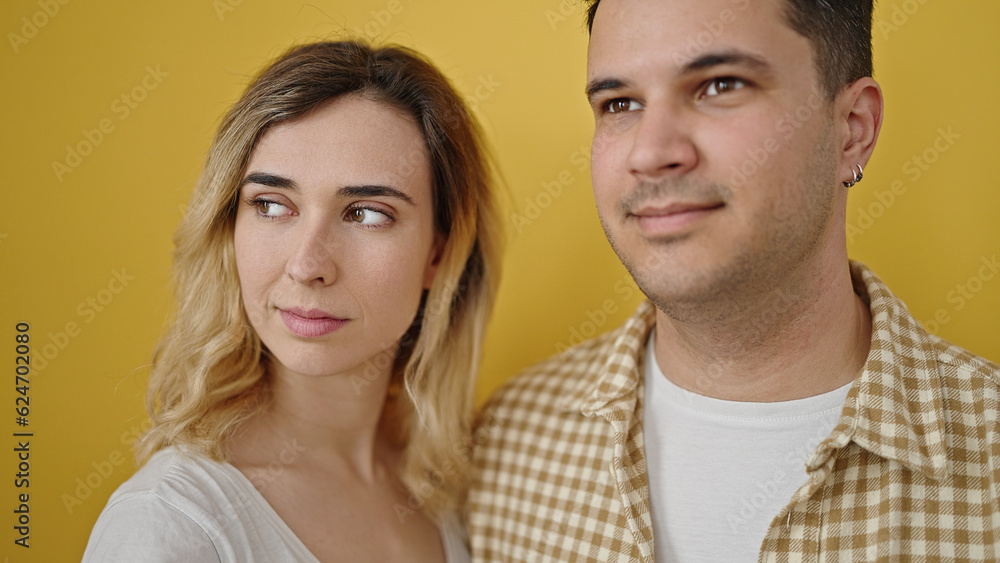 Man and woman couple smiling confident standing together over isolated yellow background Man and woman couple smiling confident standing together over isolated yellow background