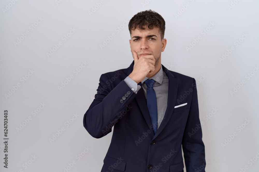 Young hispanic business man wearing suit and tie looking confident at the camera with smile with crossed arms and hand raised on chin. thinking positive. Young hispanic business man wearing suit and tie looking confident at the camera with smile with crossed arms and hand raised on chin. thinking positive.