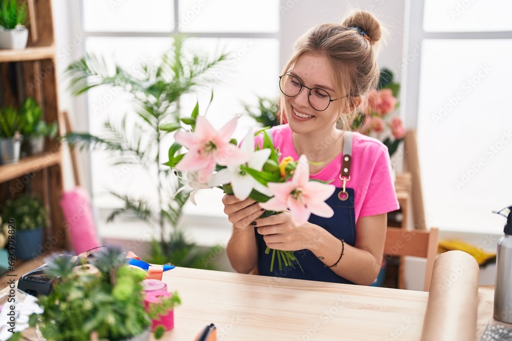 Young blonde woman florist make bouquet of flowers sitting on table at flower shop Young blonde woman florist make bouquet of flowers sitting on table at flower shop
