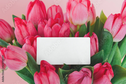 Fototapeta Naklejka Na Ścianę i Meble -  bouquet of pink fresh tulips on pink background, craft envelope with gift greeting card inside, holiday concept, space for text