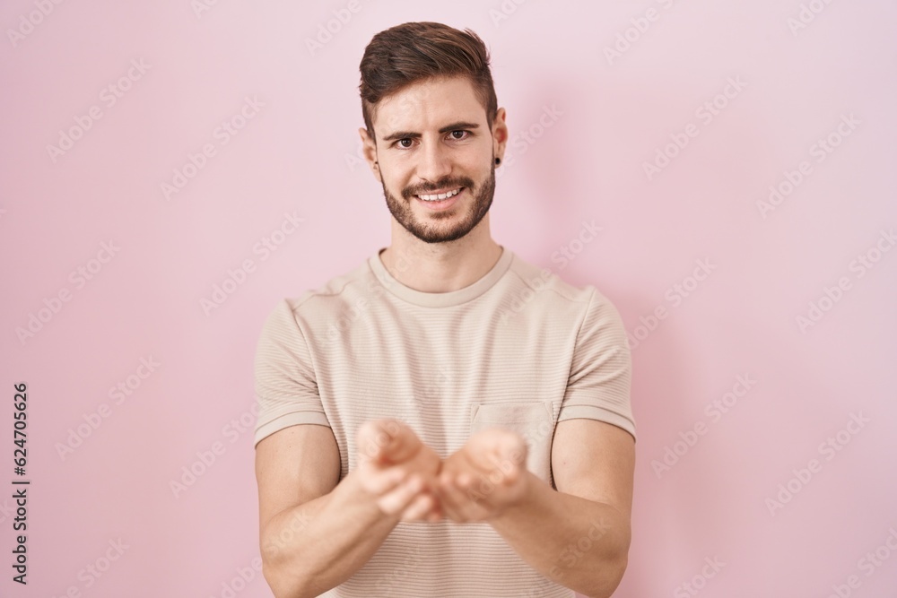Hispanic man with beard standing over pink background smiling with hands palms together receiving or giving gesture. hold and protection Hispanic man with beard standing over pink background smiling with hands palms together receiving or giving gesture. hold and protection