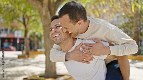 Two men couple smiling confident standing on back at park