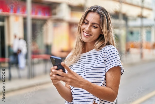 Young blonde woman smiling confident using smartphone at street © Krakenimages.com
