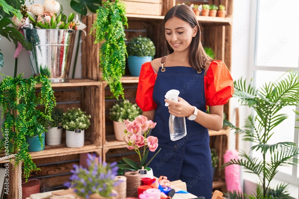 Young beautiful hispanic woman florist using diffuser working at florist