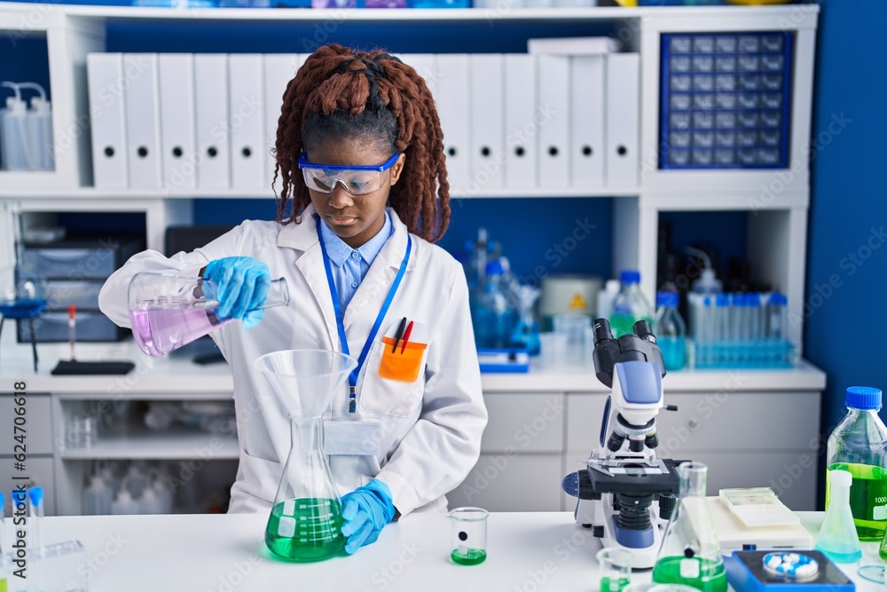 African american woman scientist pouring liquid on test tube at laboratory African american woman scientist pouring liquid on test tube at laboratory
