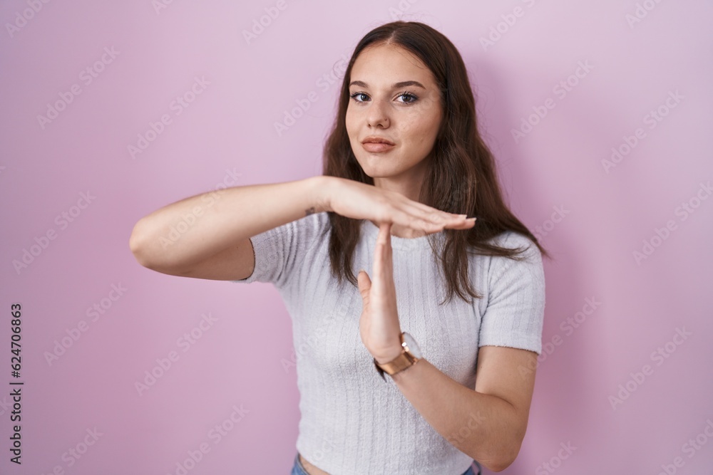 Young hispanic girl standing over pink background doing time out gesture with hands, frustrated and serious face Young hispanic girl standing over pink background doing time out gesture with hands, frustrated and serious face