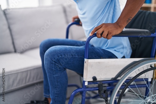 Young latin man sitting on wheelchair at home