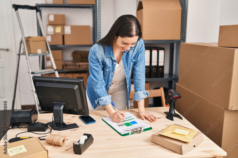 Young beautiful hispanic woman ecommerce business worker writing on document at office Young beautiful hispanic woman ecommerce business worker writing on document at office