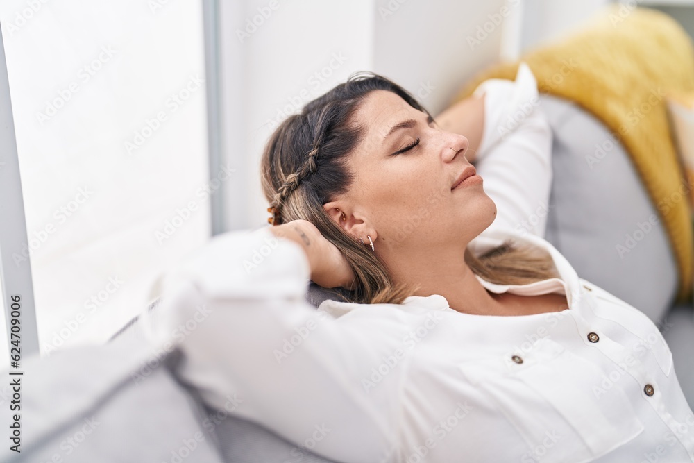 Young hispanic woman relaxed with hands on head sitting on sofa at home Young hispanic woman relaxed with hands on head sitting on sofa at home