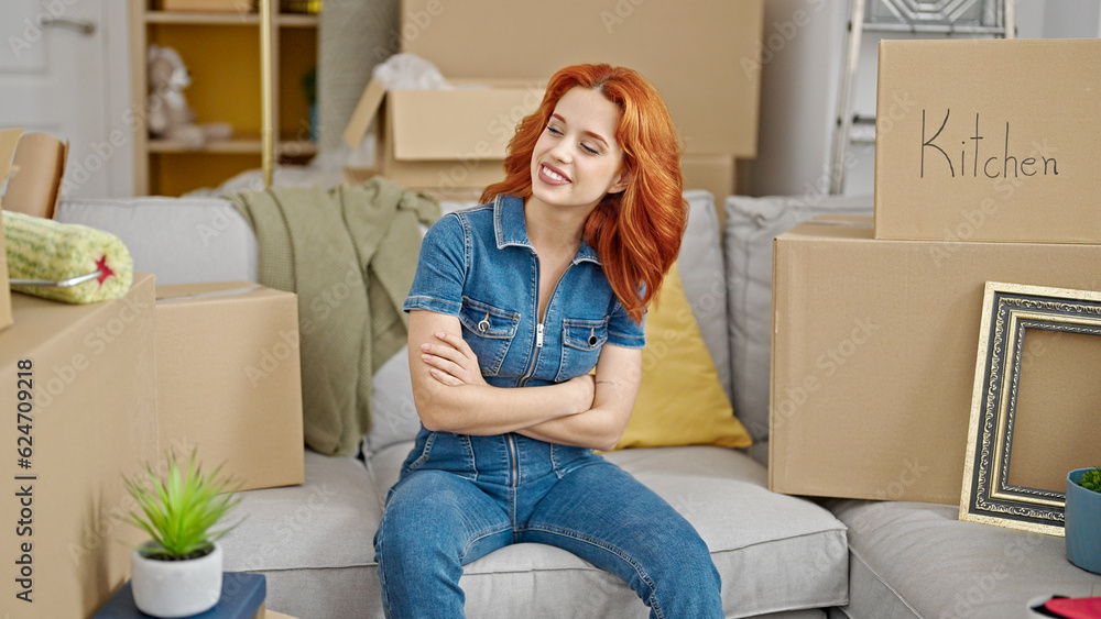 Young redhead woman smiling confident sitting on sofa with arms crossed gesture at new home Young redhead woman smiling confident sitting on sofa with arms crossed gesture at new home