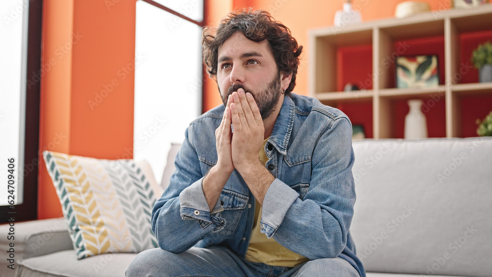 Young hispanic man stressed sitting on sofa at home Young hispanic man stressed sitting on sofa at home